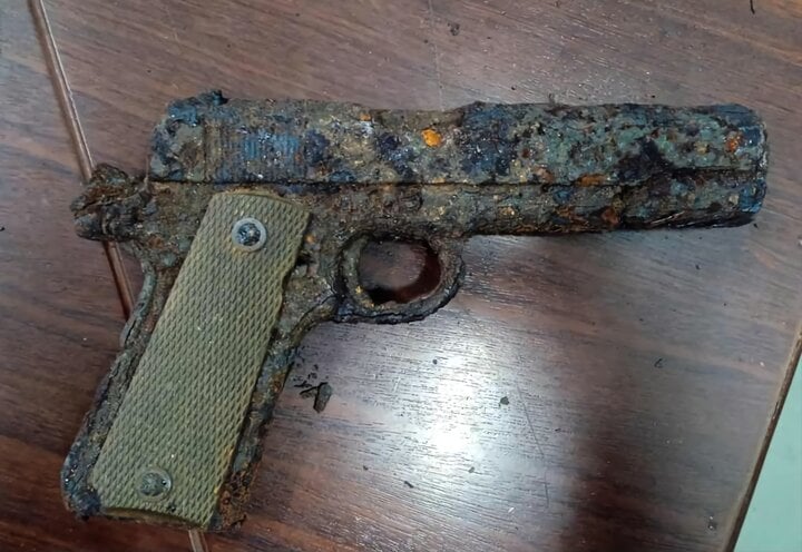 Khẩu súng ngắn quân dụng rỉ sét được phát hiện vùi dưới cát trong rừng phòng hộ ở Thừa Thiên - Huế. (Ảnh: CA phường Thuận An).